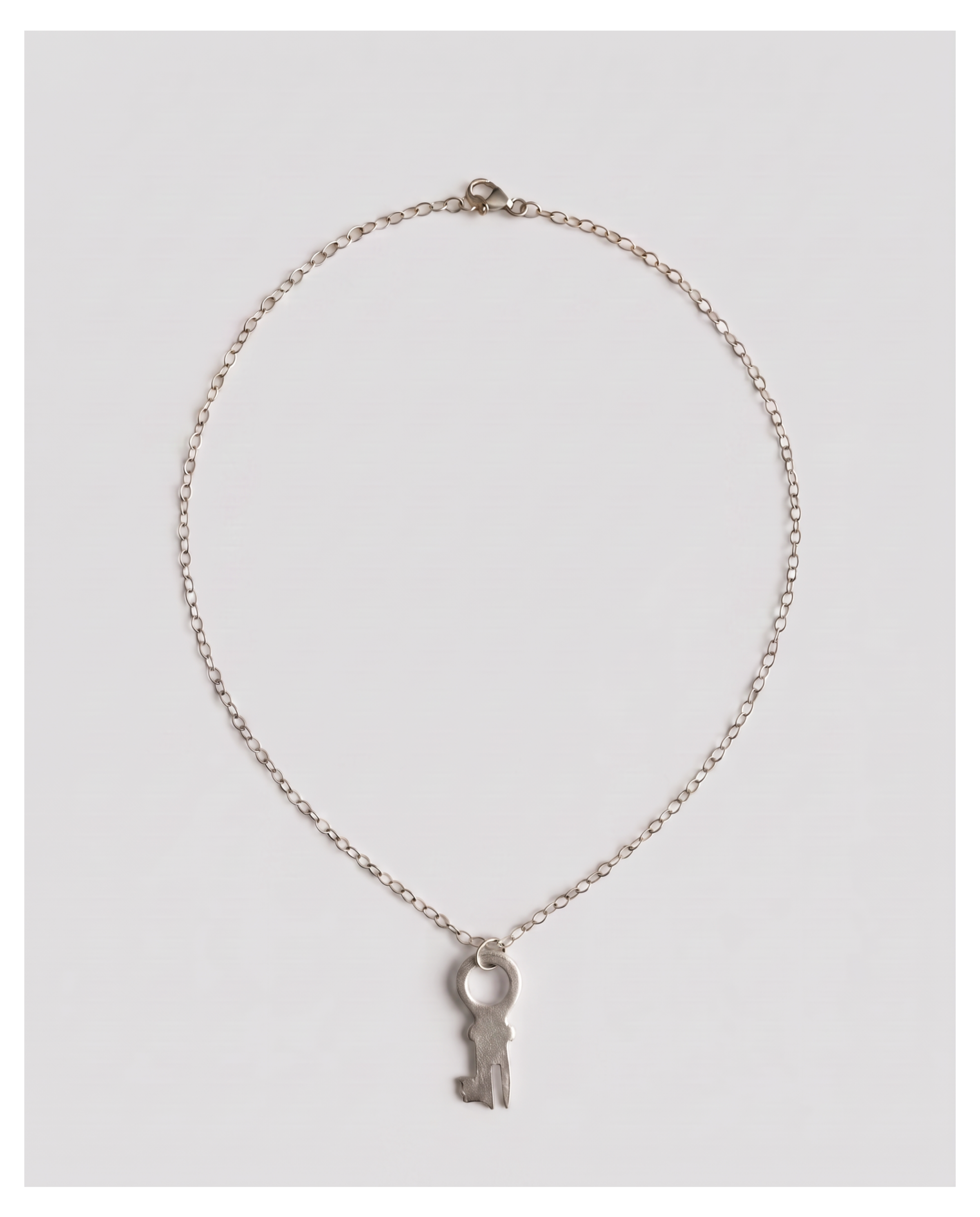 A delicate silver chain necklace featuring a small key-shaped pendant, displayed against a light gray background.